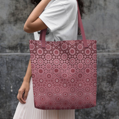 Person holding a pink patterned tote bag against a gray stone wall.